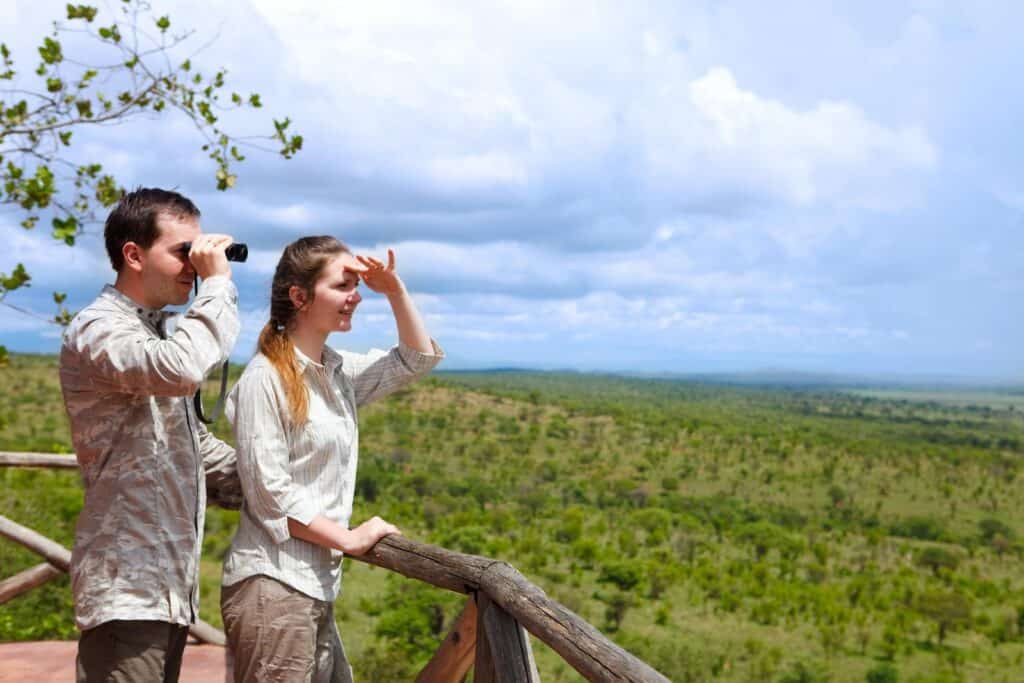 Couple wearing neutral African safari clothes viewing wildlife in the savannah